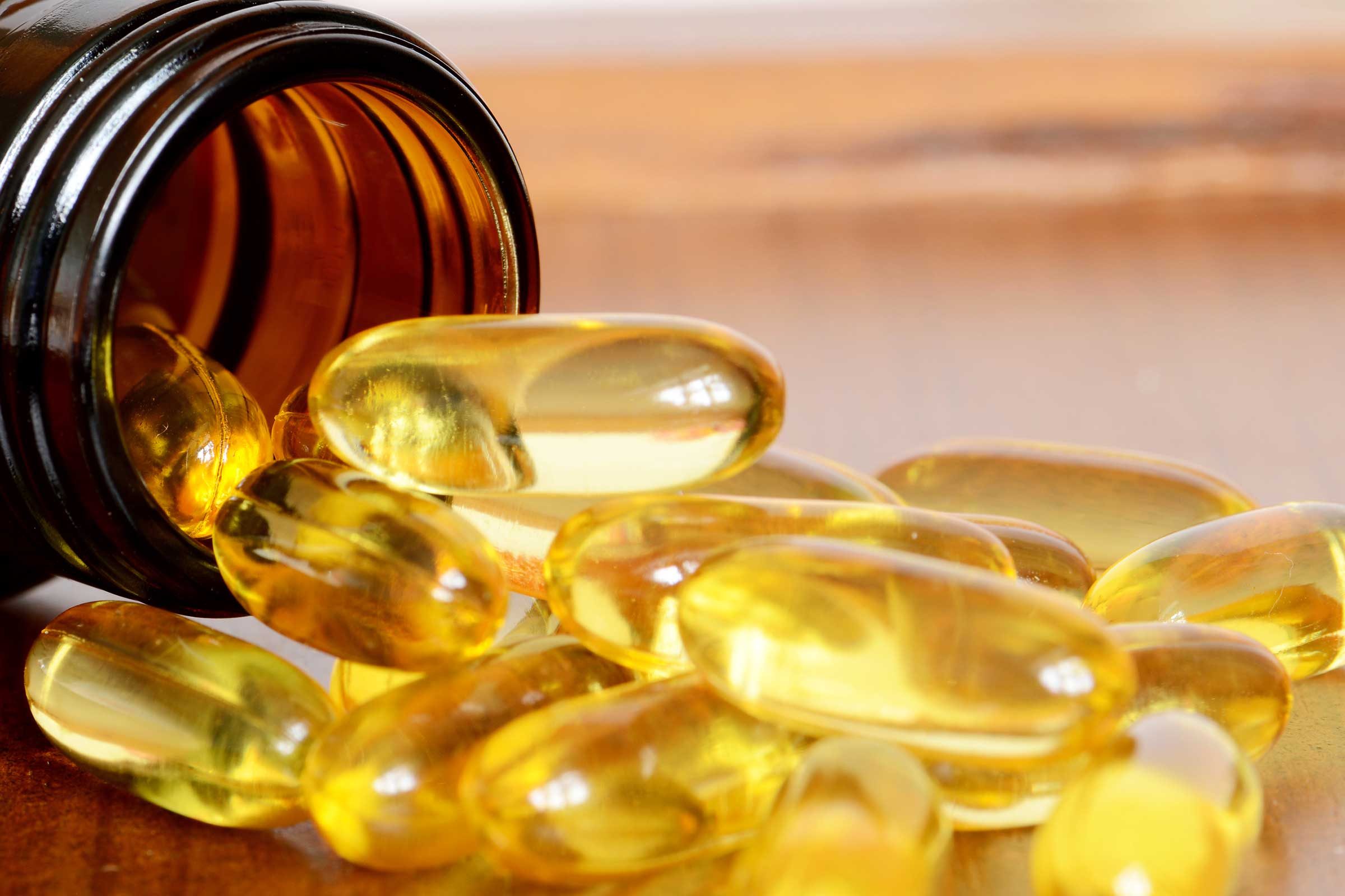 yellow translucent capsules spilling out of a bottle
