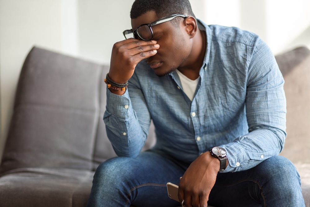 man massaging bridge of his nose with his eyes closed