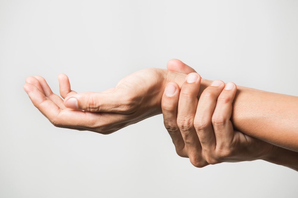 holding wrist as if in pain