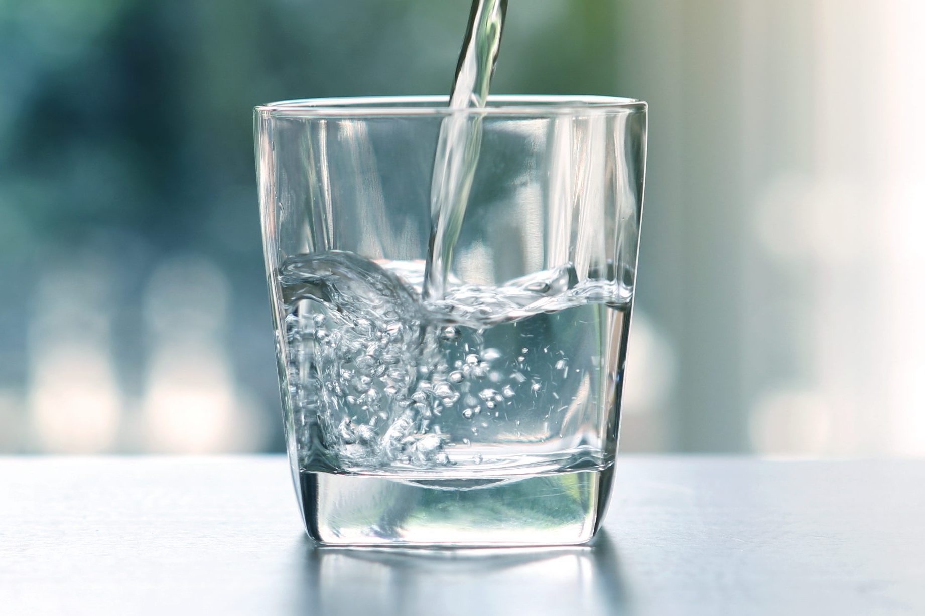 Close up the pouring purified fresh drink water from the bottle on table in living room