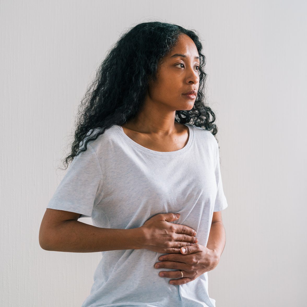 Young African-american patient complaining about belly ache to mature female doctor