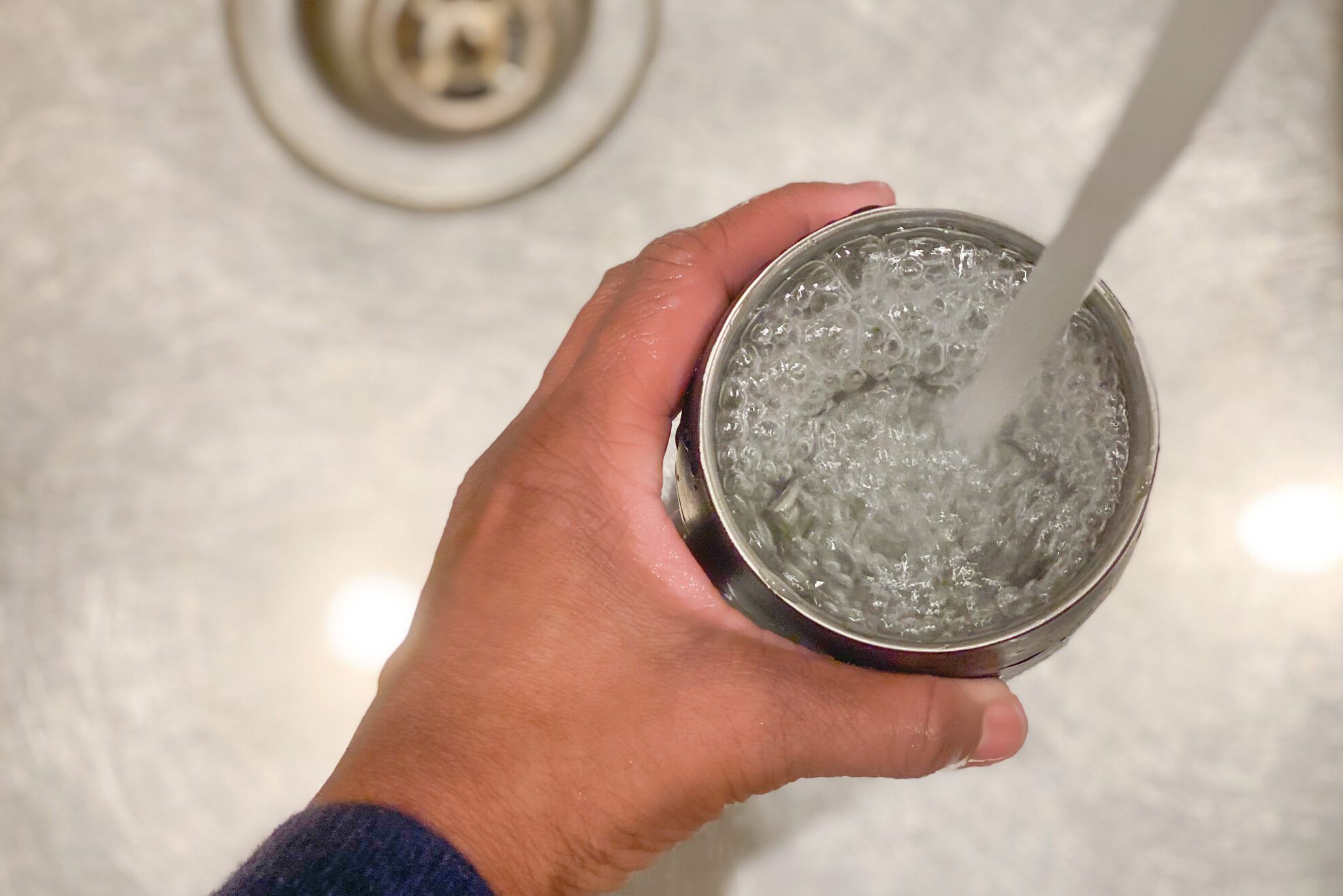 unrecognizable african-american woman fills a reusable cup with tap water