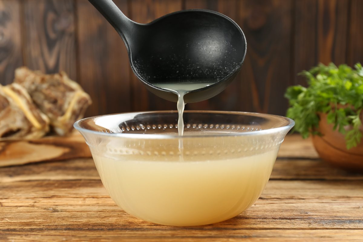 pouring homemade broth in a large glass bowl