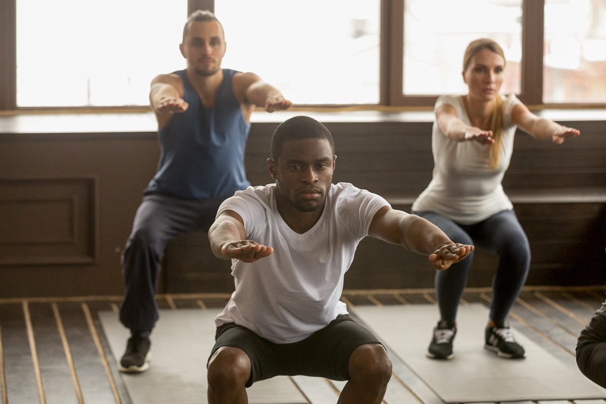 man doing squat exercise at group fitness training