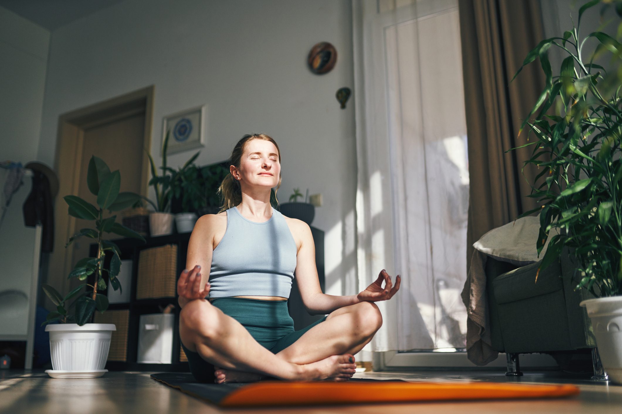Woman enjoys a peaceful moment in meditation, embraced by the warmth of her home.