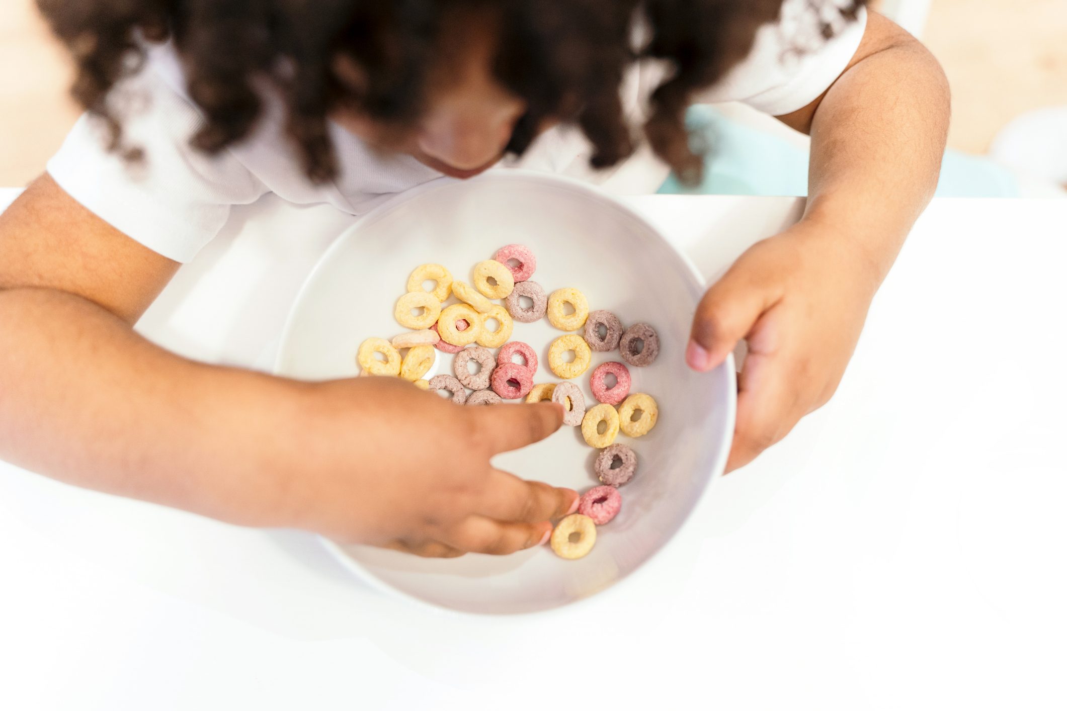 Unrecognizable Little Boy Eating A Bowl Of Colorful Cereals In The Kitchen.